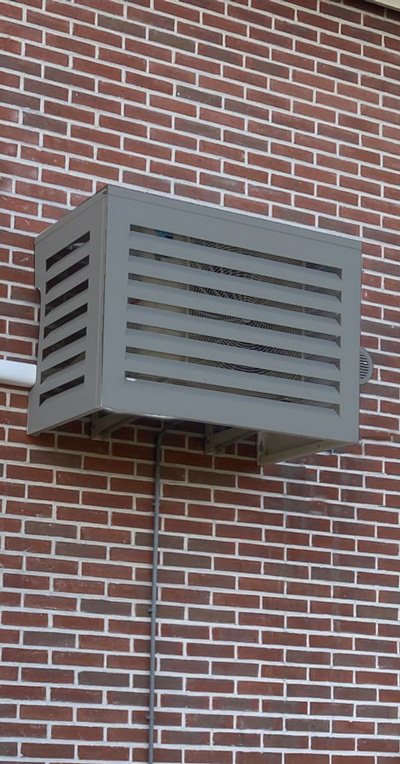 Buitenunit aan de zijgevel met omkasting om minder zichtbaar te zijn en voor minder geluidsoverlast te zorgen