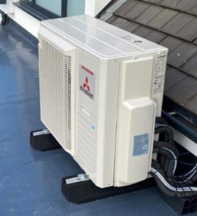 Airco buitenunit op een plat dak voor bij een tussenwoning